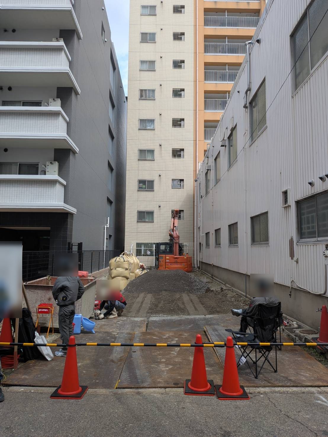 前面道路から見た敷地。カラーコーンとバーで区画し、通行の安全を確保しています。